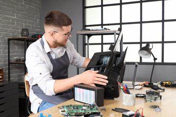 Male technician repairing printer in service center