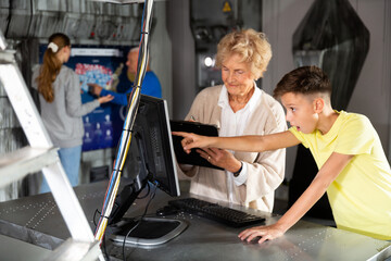 Portrait of grandmother with her grandson at computer, thinking about solving puzzle in the quest...