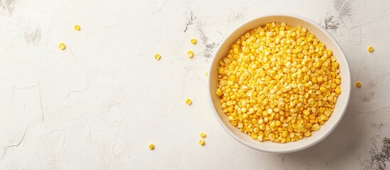 Bowl of yellow split peas on light background with scattered peas and copy space for text