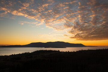 Dramatic and colorful sunset over Orcas Island in the San Juan Islands archipelago of Washington State. Aerial drone view of an amazing cloudscape as seen from Lummi Island located in the Salish Sea.