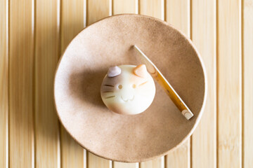 A piece of delicious Japanese confectionery on ceramic plate on wooden table.