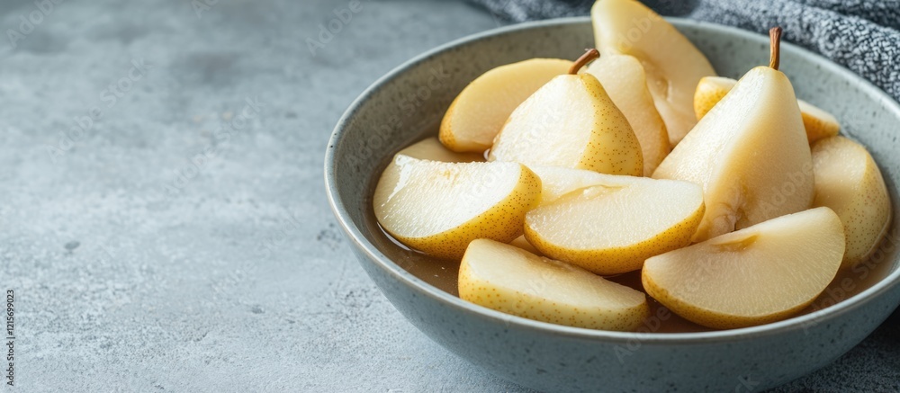 Poster sliced pears in a gray bowl on a textured surface with copy space for text placement