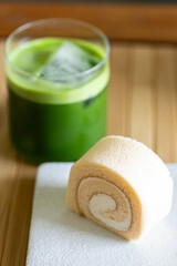 Refreshing matcha drink with ice on wooden table background.