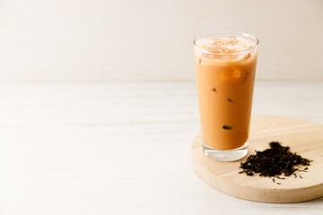 Iced Thai milk tea in a glass on wooden table.