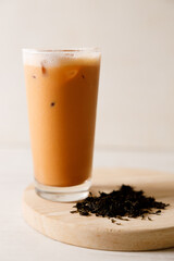 Iced Thai milk tea in a glass on wooden table.