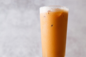Iced Thai milk tea in a glass on wooden table.
