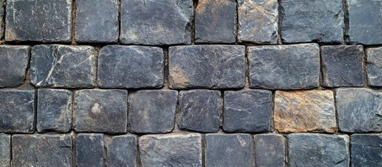 Obraz premium Stone wall texture with dark gray rectangular stones arranged in a uniform pattern, suitable for backgrounds or architectural design. Copy Space.