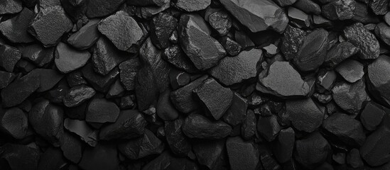 Black crushed stone texture background with various sizes of jagged pieces, ideal for graphic design, with Copy Space available.
