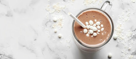 Hot chocolate in a glass mug topped with marshmallows on a marble surface with copy space for text.