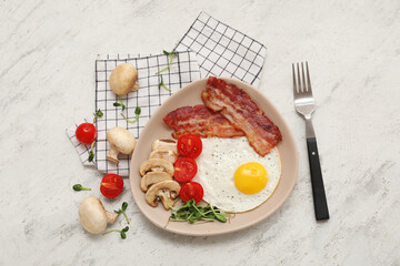 Plate with fried egg, bacon, mushrooms, microgreens and tomatoes on white grunge background. Top view