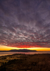 Dramatic and colorful sunset over Orcas Island in the San Juan Islands archipelago of Washington State. Aerial drone view of an amazing cloudscape as seen from Lummi Island located in the Salish Sea.