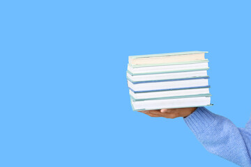 Female hands holding books on blue background