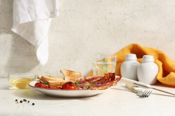 Fried bacon with toasts and dried tomatoes on plate on table against white background