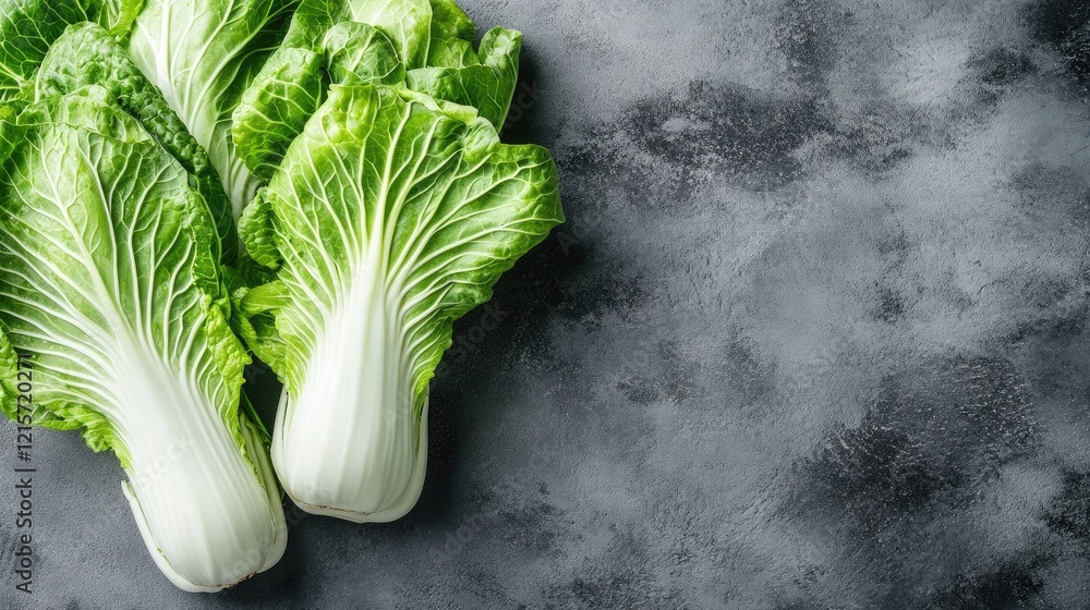 Poster fresh napa cabbage leaves on gray textured stone surface with copy space for text or design elements