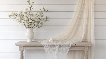 Elegant banquet table with sheer lace draping on white shiplap backdrop featuring floral arrangement in a vase for serene decor setting