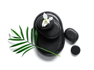 Composition with black spa stones, flower and palm leaf on white background