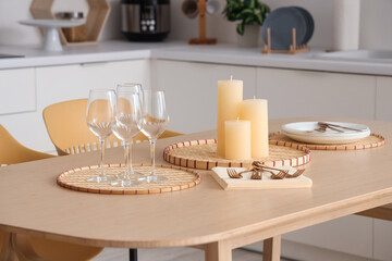 Candles on tray and glasses on table in modern kitchen