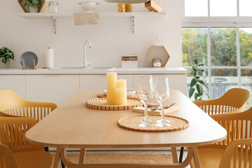 Candles on tray and glasses on table in modern kitchen