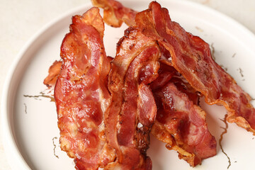 Plate with fried bacon rashers on white background, closeup