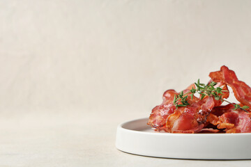 Plate with fried bacon rashers on white background