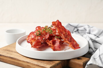 Plate with fried bacon rashers on white background