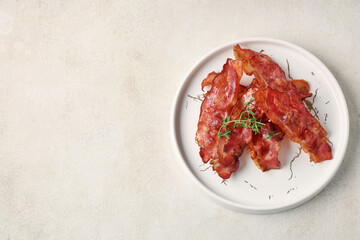 Plate with fried bacon rashers on white background