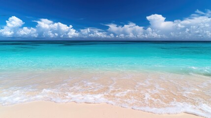 Obraz premium Tranquil summer beach scene with turquoise ocean waves, soft sandy shore, and vibrant cloudy sky for serene vacation imagery.
