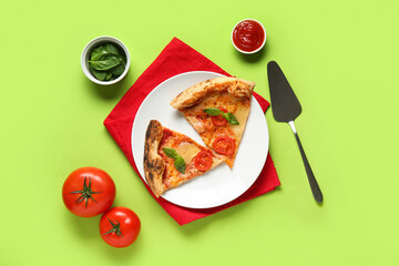 Plate with pieces of tasty pizza Margarita and bowl of basil on green background