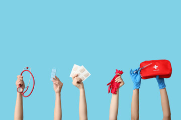 Female hands with mustard plasters, stethoscope, pill box, gloves, syringe and first aid kit on blue background