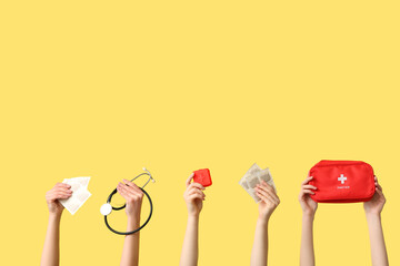 Female hands with mustard plasters, stethoscope, pill box and first aid kit on yellow background