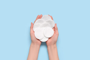 Female hands with many cotton pads on blue background © Pixel-Shot