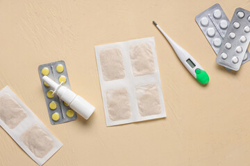 Mustard plasters with nasal drops, pills and thermometer on yellow background