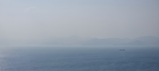 Un mar en calma, un barco pesquero moviéndose a través de la niebla de la mañana.
