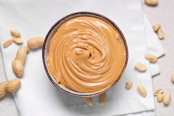 Bowl of tasty peanut butter with nuts on white background