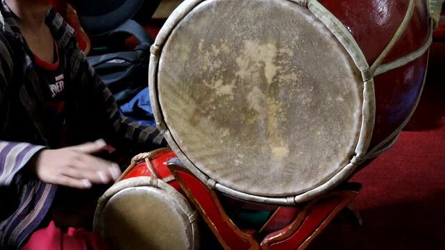 A child playing a kendang one of the instruments in a gamelan ensemble