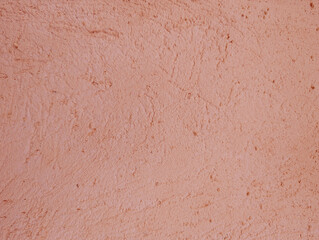 Salmon pink rough scratched cement or concrete wall texture or background with uneven and irregular grooves and reliefs. Mediterranean rustic architectural outdoor style.