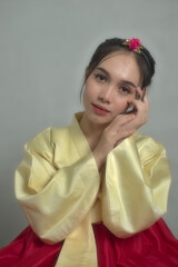 Young Asian Woman wearing soft gold hanbok and red chima, a traditional Korean dress