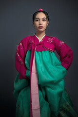 Young woman wearing pink, fuchsia and teal hanbok, a traditional Korean dress.
