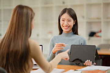 Two Asian business women discuss and discuss company paperwork. in the office room