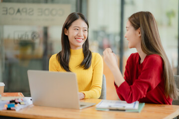 Two Asian business women discuss and discuss company paperwork. in the office room