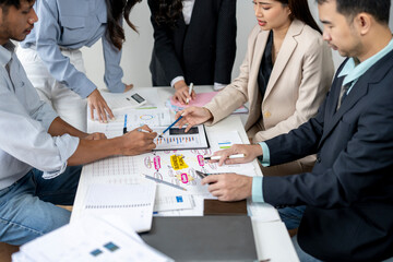 A group of people are sitting around a table with papers and pens