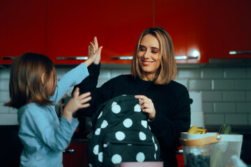 Mother and Daughter Ready for School Making High Five Gesture. Cheerful family doing morning...