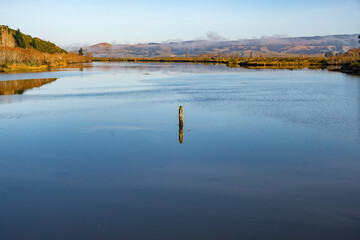 The river Taieri at sunrise where it becomes an estuary and the Historic Henley suspension bridge over the river Taieri at Otokai in the early morning