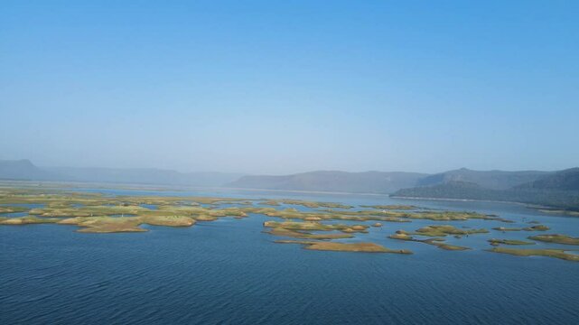Stunning aerial view of Karamchat Dam, with the calm waters reflecting the surrounding greenery.