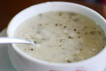 A Creamy Soup Presented in a White Bowl Accompanied by a Spoon