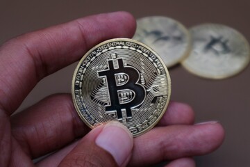 A man's hand holds bitcoin