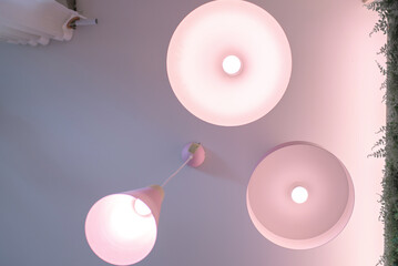 The lamps that are hung on the ceiling in the café have a beautiful pink color.