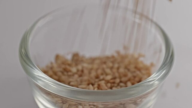 sesame seeds falling in small glass bowl, 4k, stable shot