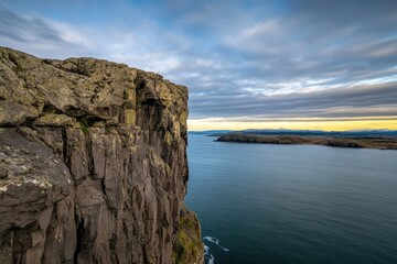 Dramatic Landscape of Coastal Cliff Overlooking Tranquil Waters at Sunset with Breathtaking Skies and Rugged Natural Texture in Serene Environment