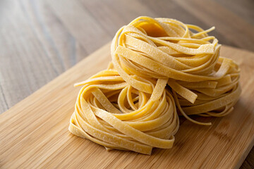 A nest of uncooked tagliatelle on a wooden surface